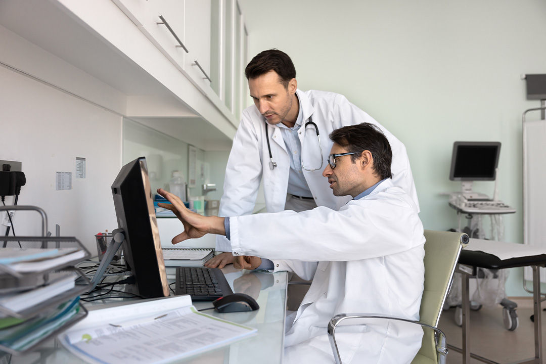 Male doctors using computer while standing in pharmacy at hospital