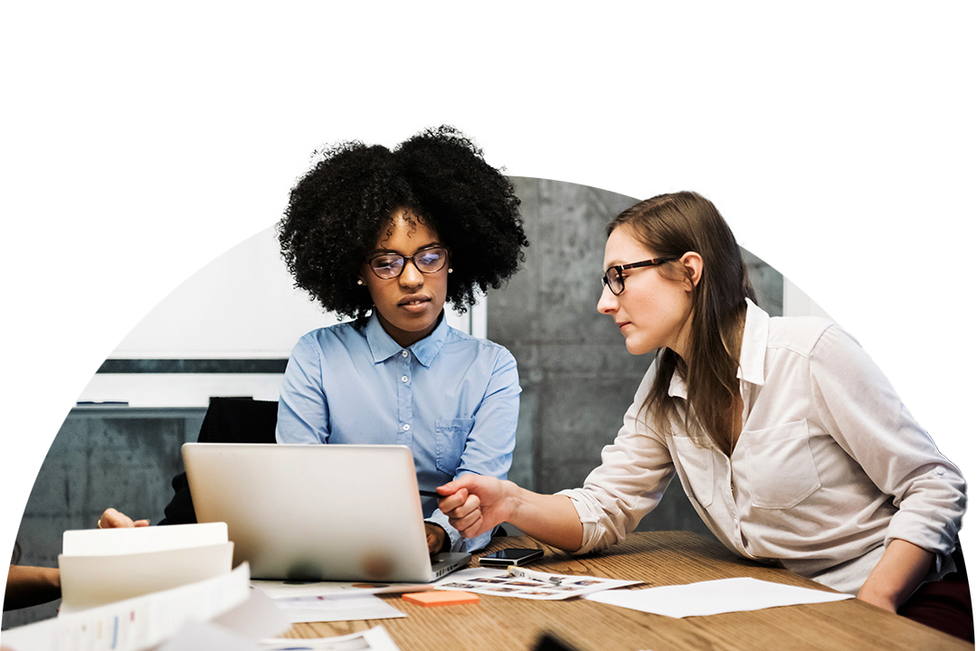 Two people reviewing content together on a laptop at a desk
