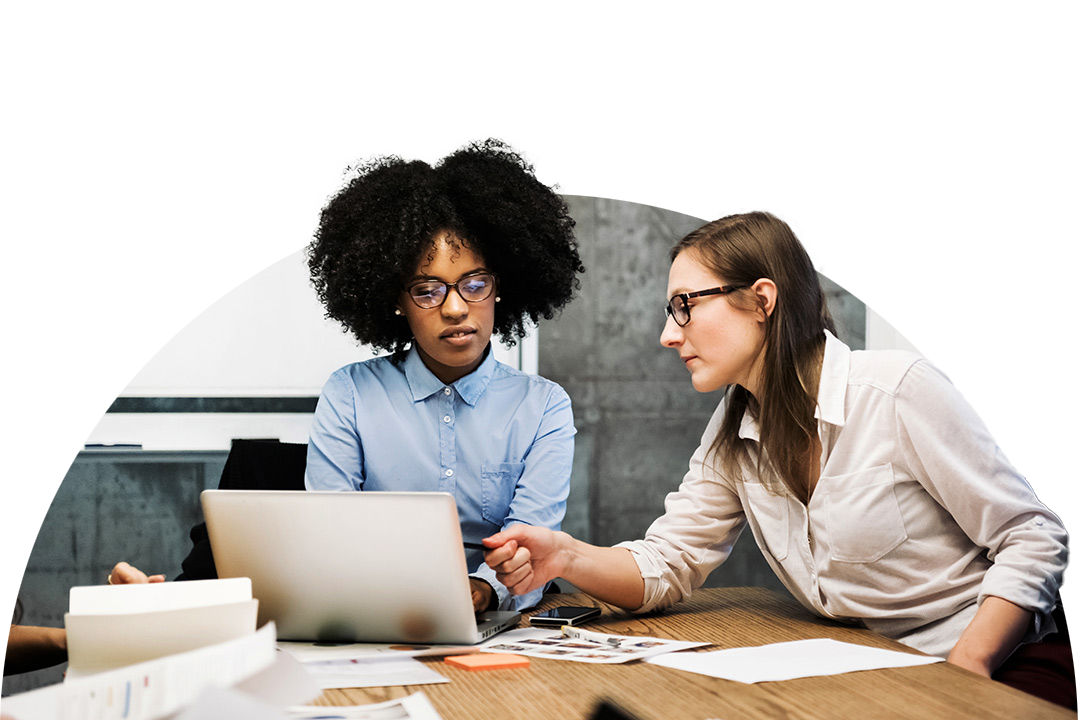 Two people reviewing content together on a laptop at a desk